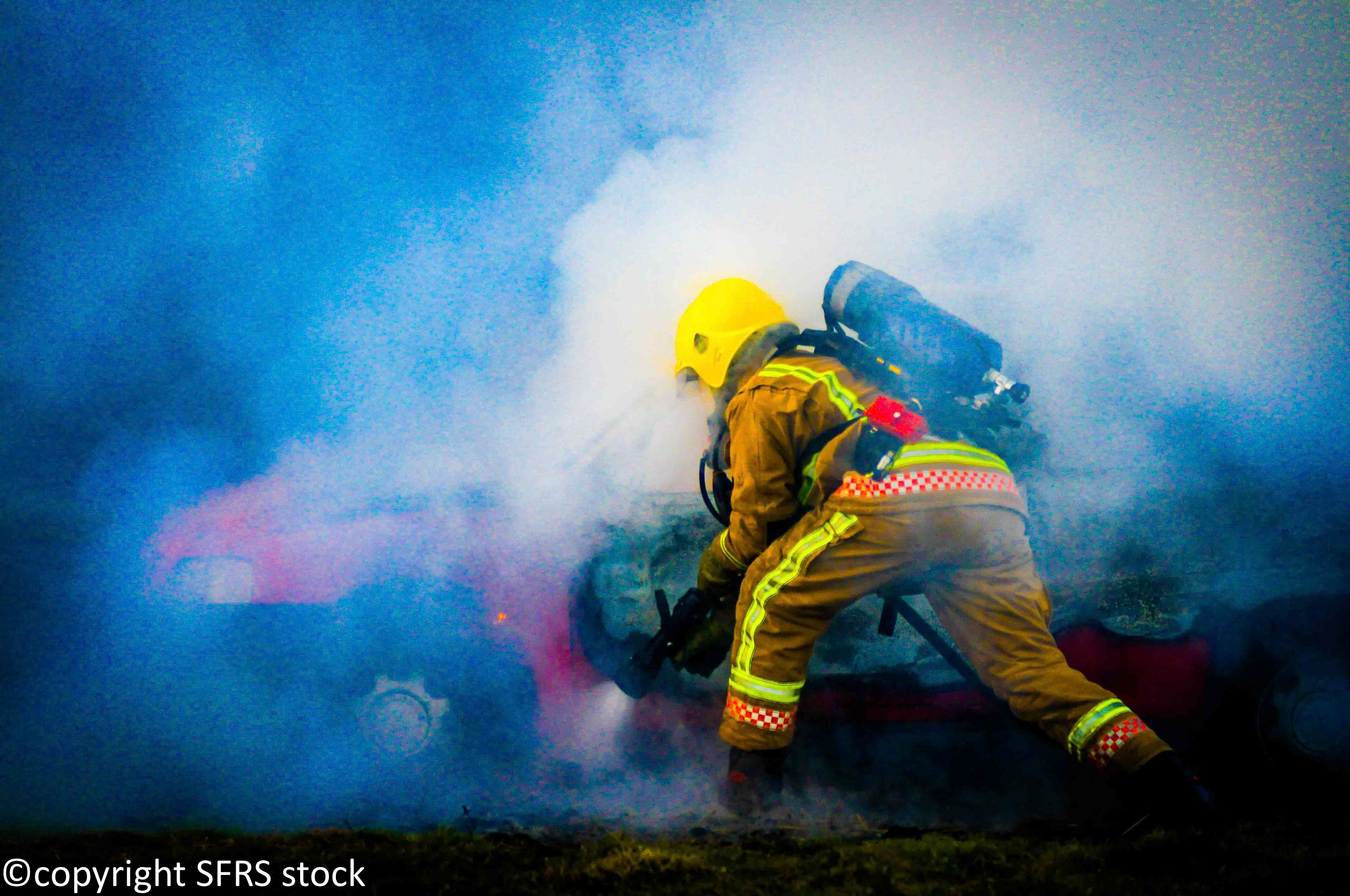 Firefighter sawing into side of car