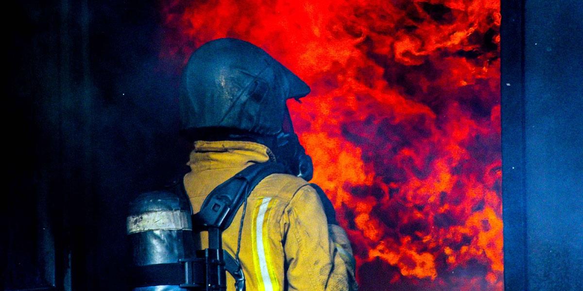 Firefighter in breathing apparatus tackling red flames