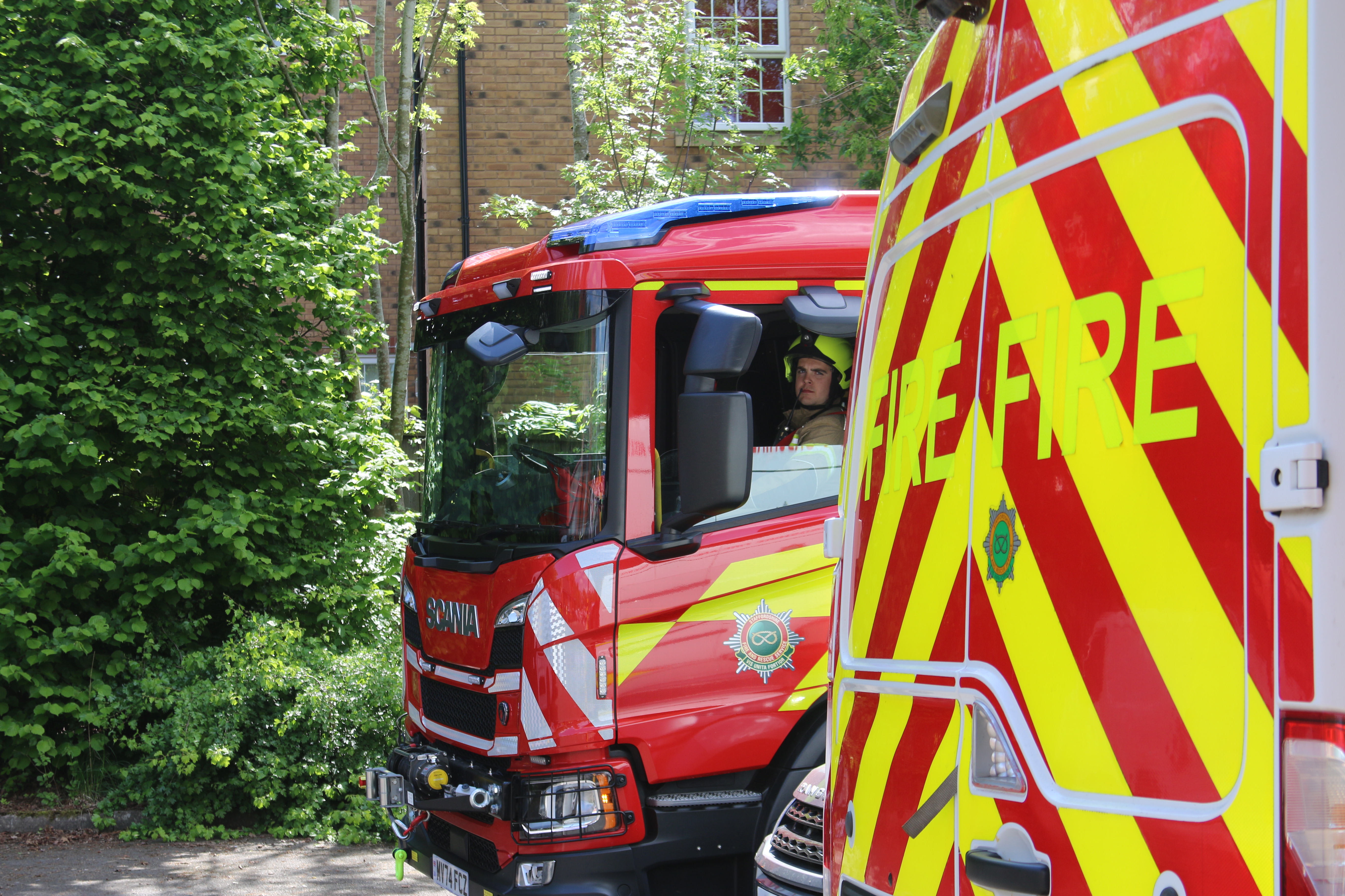 Firefighter sat in a fire appliance with the window down, looking out.