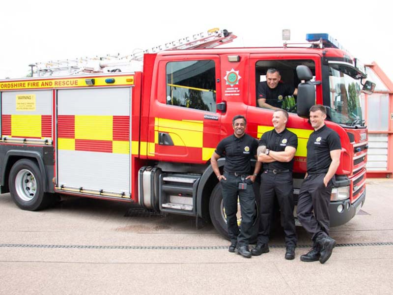 Firefighters standing by fire appliance